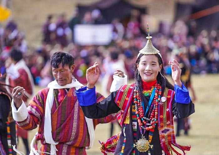 Two people in traditional Bhutanese attire dancing at a cultural festival